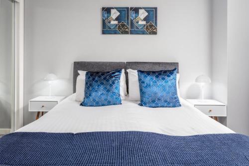 a bedroom with a blue and white bed with blue pillows at Millbrae Residence - Donnini Apartments in Ayr