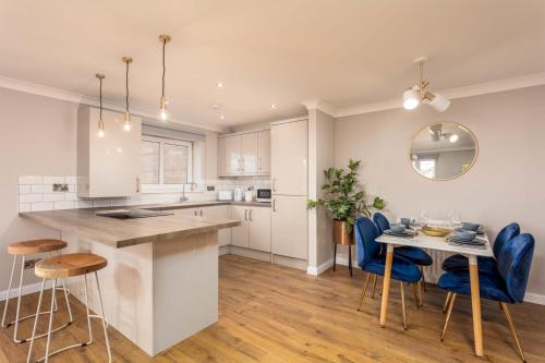 a kitchen and dining room with a table and blue chairs at Waverley Suite No57 - Donnini Apartments in Ayr