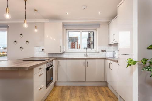 a kitchen with white cabinets and a window at Waverley Suite No57 - Donnini Apartments in Ayr