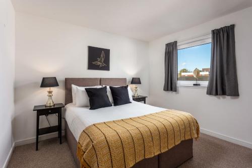 a bedroom with a large bed with two lamps and a window at Walker Suite No53 - Donnini Apartments in Kilmarnock