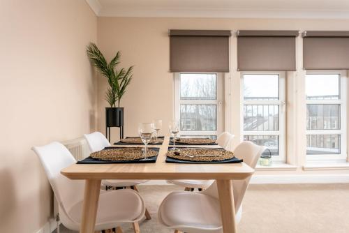 a dining room with a table and chairs and windows at The Lucas - Donnini Apartments in Ayr