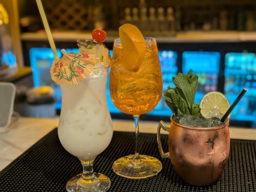 three cocktails sitting on a table in a bar at Mayfair Hotel -Isle of Wight in Shanklin