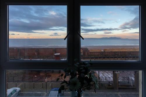 a view of the ocean from a window with a vase of flowers at Harris Retreat - Donnini Apartments in Ayr