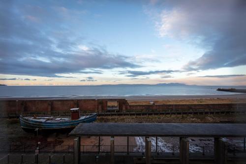 a boat sitting on the shore of a beach at Harris Retreat - Donnini Apartments in Ayr