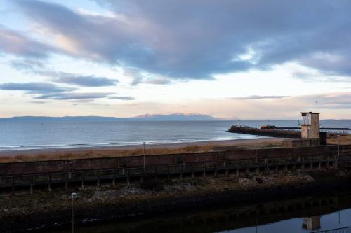 a view of a beach with a pier and the ocean at Harris Retreat - Donnini Apartments in Ayr