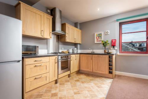 a large kitchen with wooden cabinets and a window at Elliot Suite No15 - Donnini Apartments in Ayr
