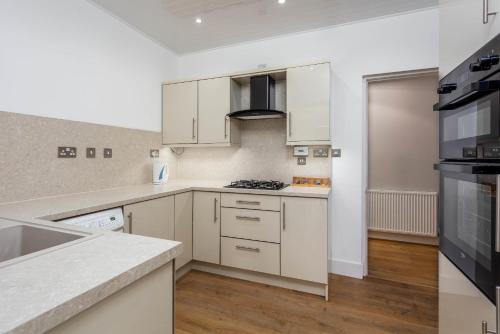 a kitchen with white cabinets and a stove top oven at Seafield House - Donnini Apartments in Ayr