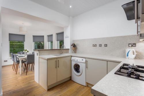 a kitchen with a washing machine and a dining room at Seafield House - Donnini Apartments in Ayr