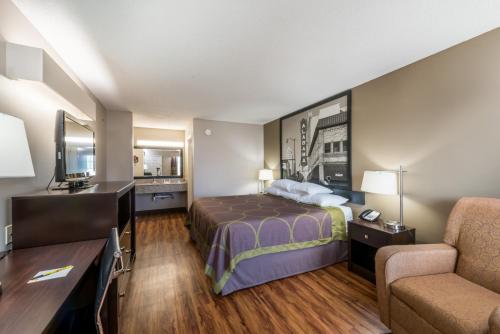 a hotel room with a bed and a chair at Super 8 by Wyndham Alexander City in Alexander City