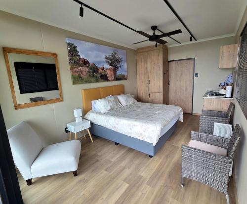 a bedroom with a bed and a chair and a tv at Lazy Hill Eco Lodge in Warmbaths