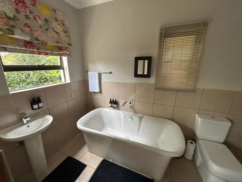 a bathroom with a white tub and a sink at Cedara Way Cottage in Hilton