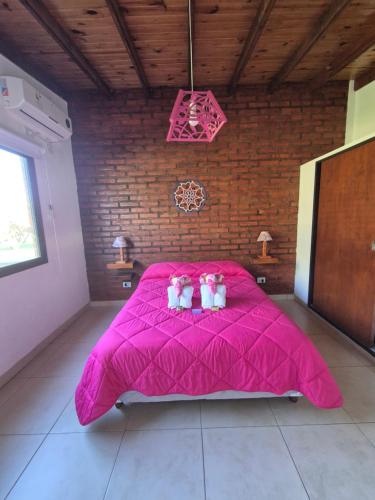 two stuffed animals sitting on a pink bed at Caranday in Cortaderas