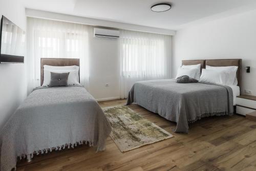two beds in a white room with wooden floors at Villa Sunce in Visoko