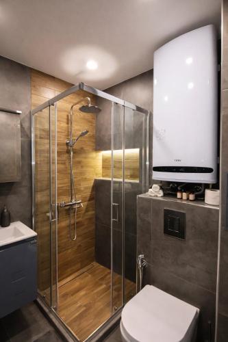 a bathroom with a shower with a toilet and a tv on the wall at Boutique apartment 4 in Plovdiv