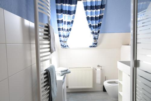 a bathroom with blue and white curtains and a toilet at Ferienwohnung Ankerpladsen Jolle in Behrensdorf