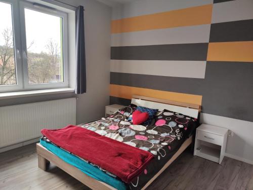 a small bedroom with a bed with a red blanket at Apartament Ela in Żywiec