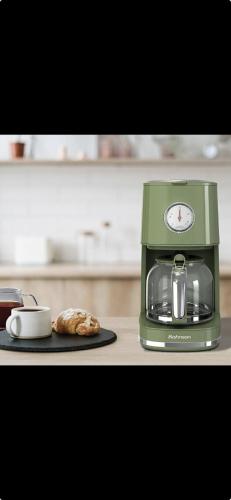 a green coffee maker sitting on a counter with a pastry at Acqui Apartments in Argostoli