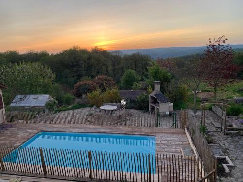 a swimming pool in a yard with a sunset in the background at Serenane in Saint-André-de-Najac
