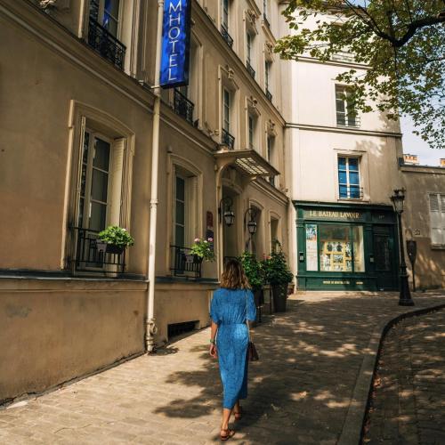 a woman in a blue dress walking down a street at Timhotel Montmartre in Paris