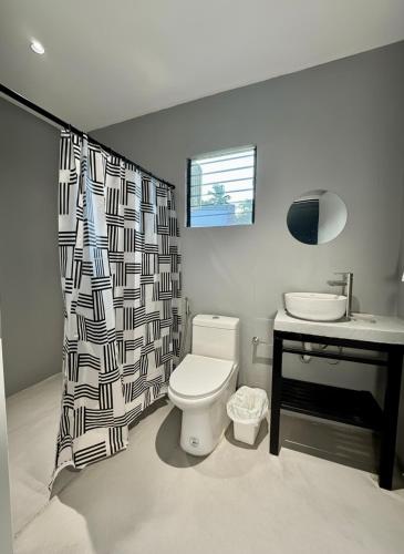 a bathroom with a toilet and a sink and a shower curtain at Siqui Pods in Siquijor