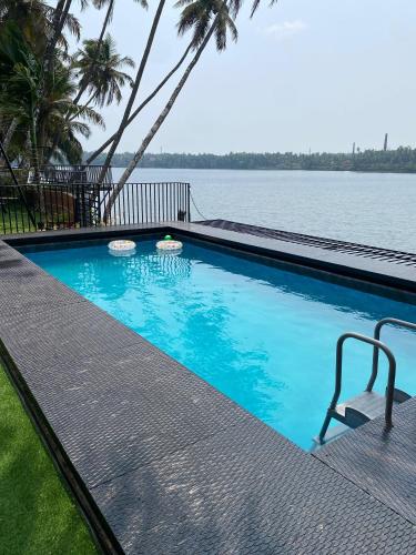 a swimming pool with a view of the water at Riveria By Vstays in Kozhikode