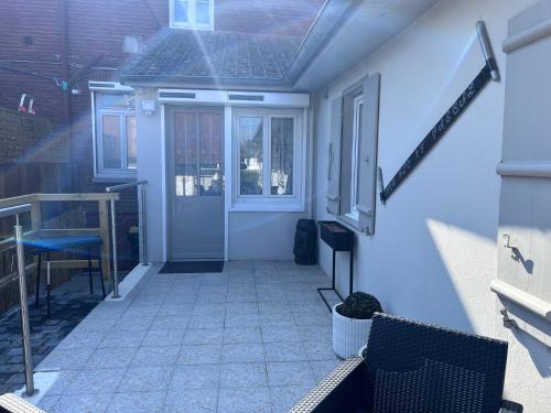 a porch with a blue door and some chairs at le relais des étangs B in Mareuil-Caubert