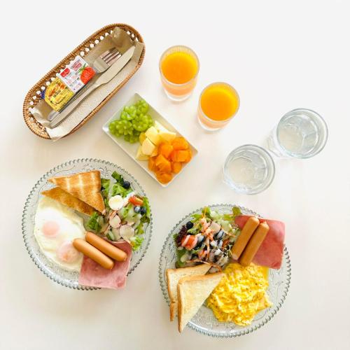 a white table with plates of food and glasses of orange juice at Longtimenosea bangsaen ลองไทม์โนซี บางแสน in Ban Bang Saen (1)
