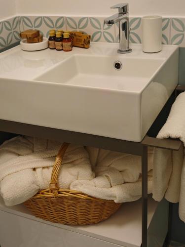 a bathroom with a sink and a basket of towels at Campagnano Rural Suite & Spa in Ischia Town