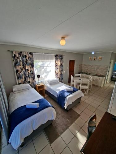 a bedroom with two beds and a table and a dining room at Lullaby Leaf in Lichtenburg