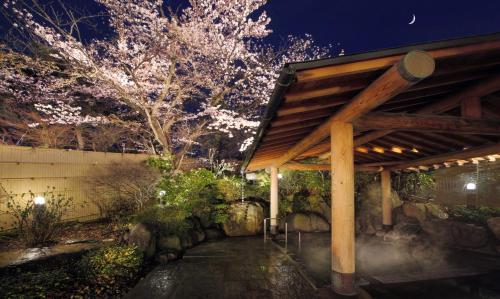 a pavilion in a garden at night with a tree at Ichiraku tendo spa & brewery in Tendo