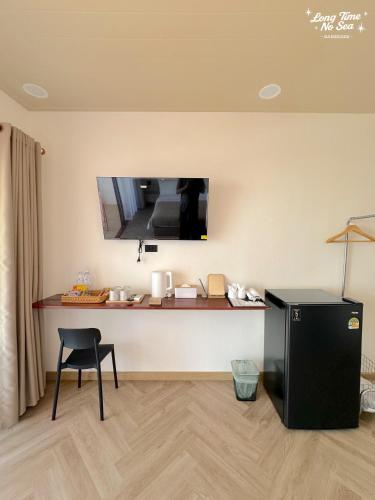 a room with a desk with a television on the wall at Longtimenosea bangsaen ลองไทม์โนซี บางแสน in Ban Bang Saen (1)