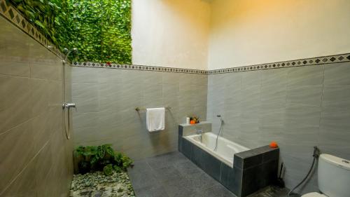 a bathroom with a bath tub and a toilet at The Oding House in Ubud