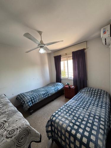 a bedroom with two beds and a ceiling fan at SIERRAS TRAVEL 2f in Villa Carlos Paz