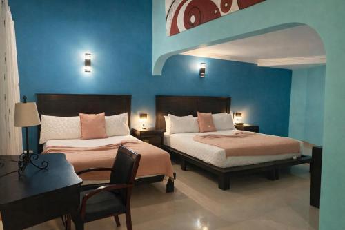 a bedroom with two beds and a table and a desk at Hotel Plaza Brisas in Punta Cana