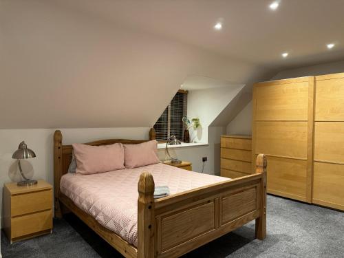 a bedroom with a wooden bed and wooden cabinets at Broadway Pool House with Sauna & Jacuzzi in Herne Bay