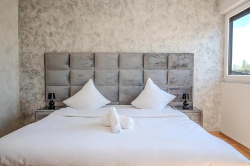 a bedroom with a large white bed with two pillows at GT Loft - Haut de Gamme - Parking Gratuit - Moderne & Spacieux - Commerces à Proximité in Bischheim