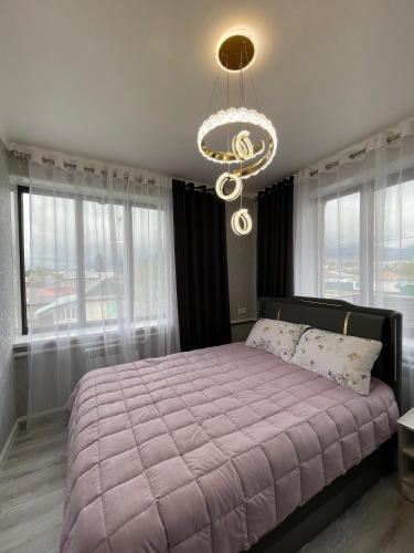 a bedroom with a large bed and a chandelier at Karakol Aksuu guest house in Teploklyuchinskoye