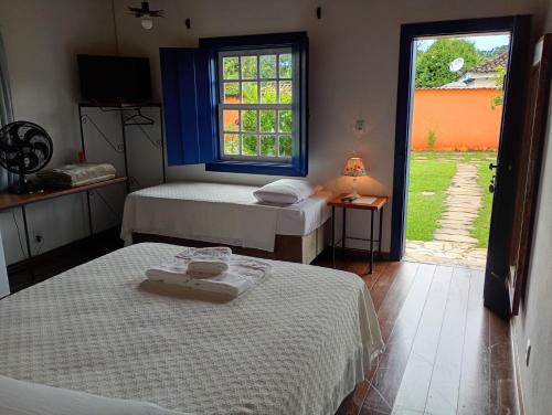 a room with two beds and a window with a view at Pousada Arco íris na Serra in Tiradentes