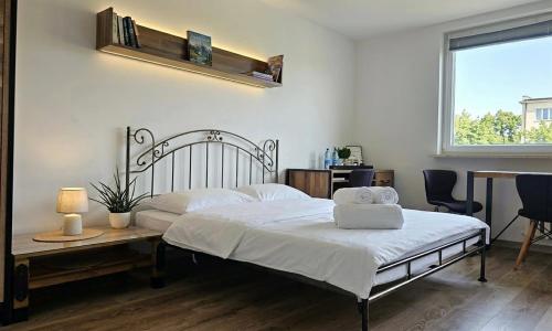 ein Schlafzimmer mit einem Bett, einem Tisch und einem Fenster in der Unterkunft Zakątek w Centrum Suwałk in Suwałki