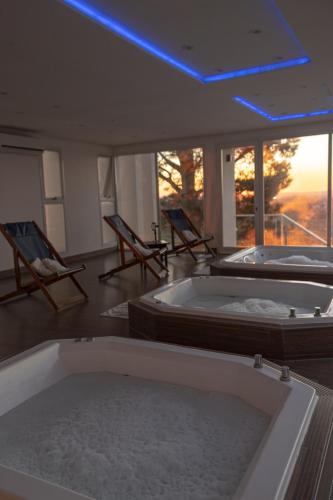 two hot tubs in a room with two chairs at Elegance Hotel Tandil in Tandil