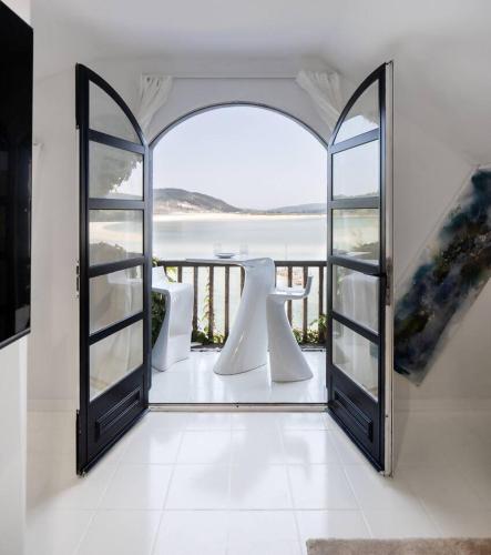 an open door to a balcony with a view of the ocean at Cabanas da Auga in Ures