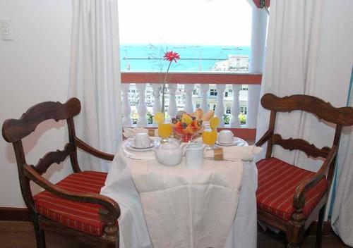 une table à manger avec deux chaises et un tissu de table blanc dans l'établissement Bed & breakfast Villa Carmo, à Salvador