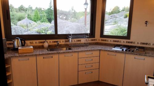 a kitchen with a sink and two windows at Aires Serranos - Suites in La Cumbrecita