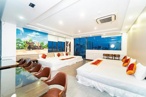 a hotel room with two beds and chairs at Khách Sạn Melanta - FLC Sầm Sơn in Sầm Sơn