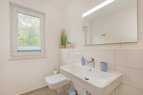 a white bathroom with a sink and a toilet at Hart Backbord in Loddin