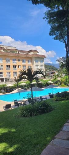 a hotel with a palm tree and a swimming pool at Serra & Sossego in Araras Petropolis
