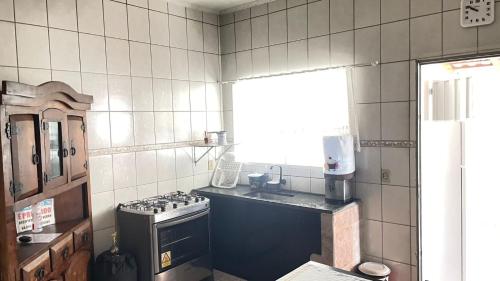 a small kitchen with a stove and a window at Casa de piscina em Delfinopolis área central 2 suítes in Delfinópolis