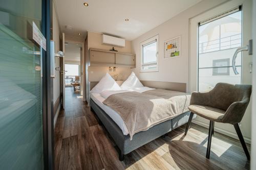 a bedroom with a bed and a chair and a window at Floatinghouse Möweninsel - LP15 in Vetschau