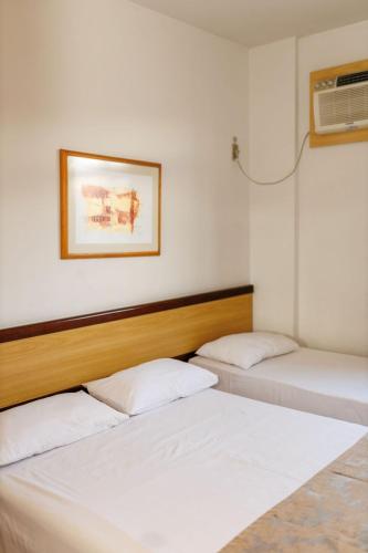 two beds in a room with white sheets at Solar Flat Hotel in Juiz de Fora