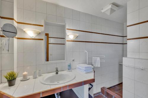 a white bathroom with a sink and a mirror at Kleine Meerzeit in Maasholm